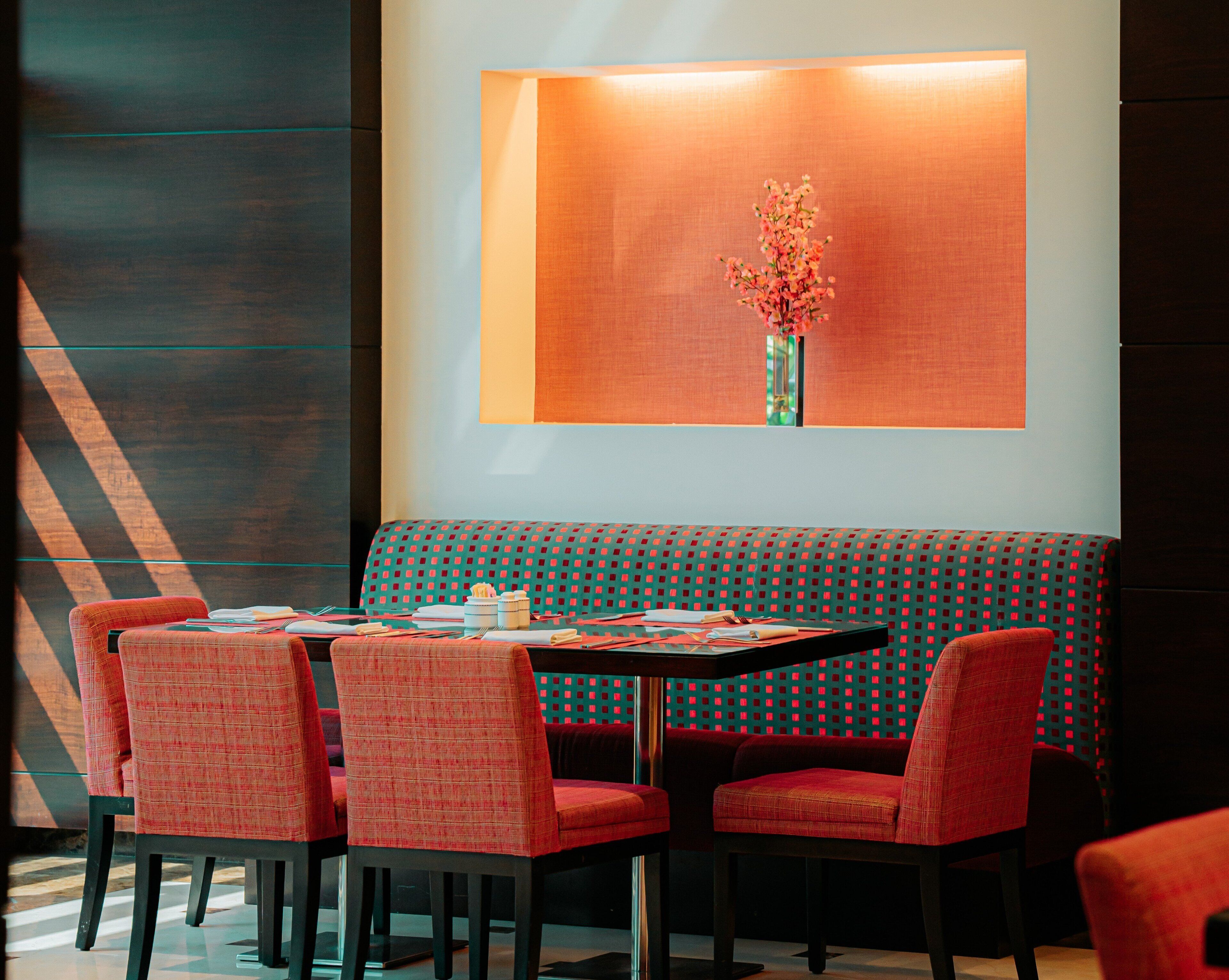 A dining area with a table set for four, a bench, and a wall-mounted vase with flowers.