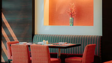 A dining area with a table set for four, a bench, and a wall-mounted vase with flowers.