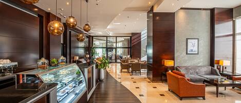 Un hall de hotel con una recepción, zona de estar y vista al interior.