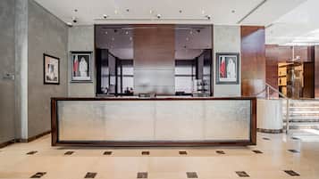 A reception area with a marble floor, framed portraits, and a staircase leading to an upper level.