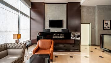 A modern lobby with a sofa, armchair, and a reception desk labeled 'BUSINESS CENTER'.