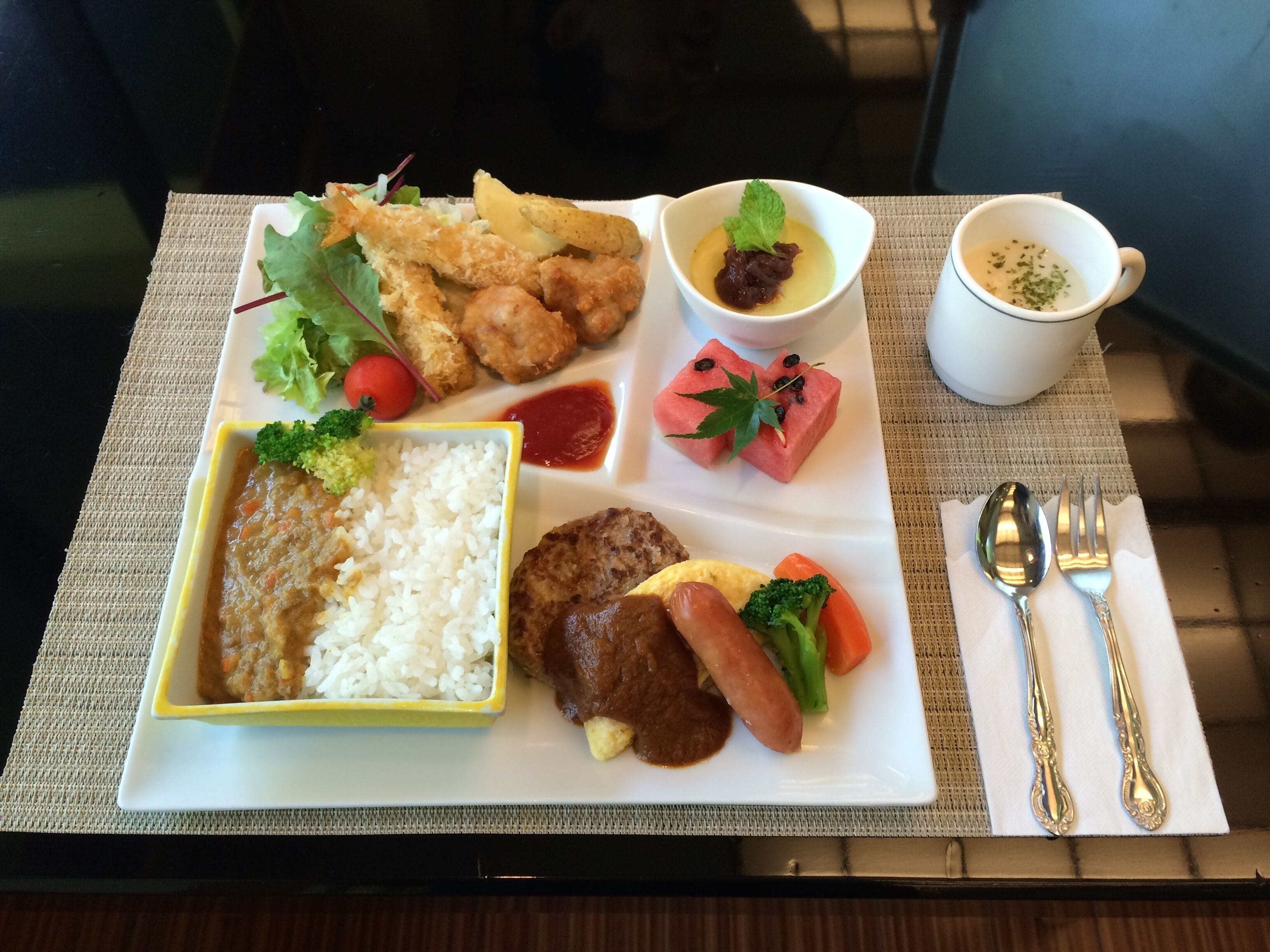 A meal tray with various dishes including rice, meat, vegetables, and a dessert.