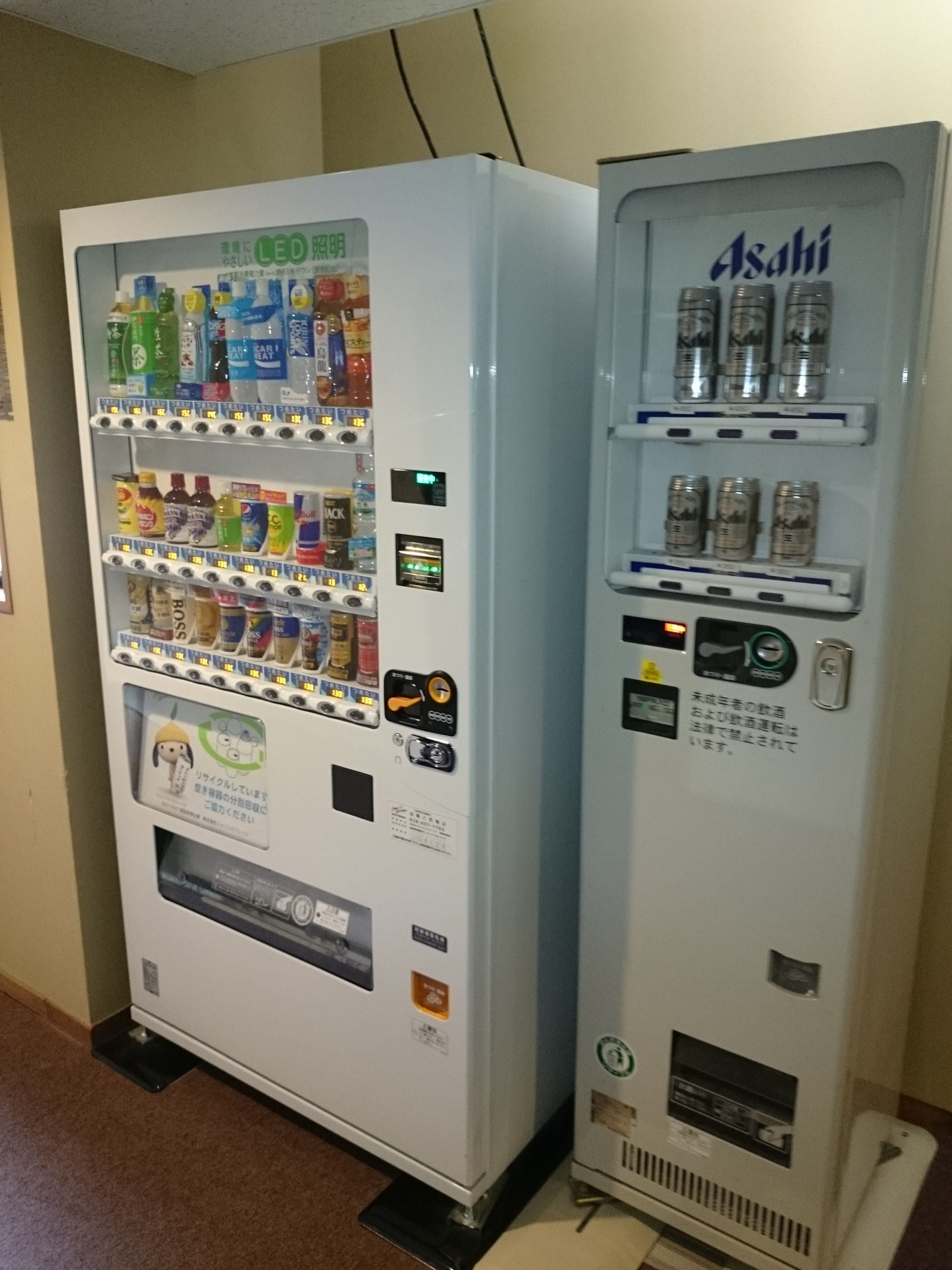 A vending machine with a variety of drinks and snacks, and a separate Asahi beer vending machine.