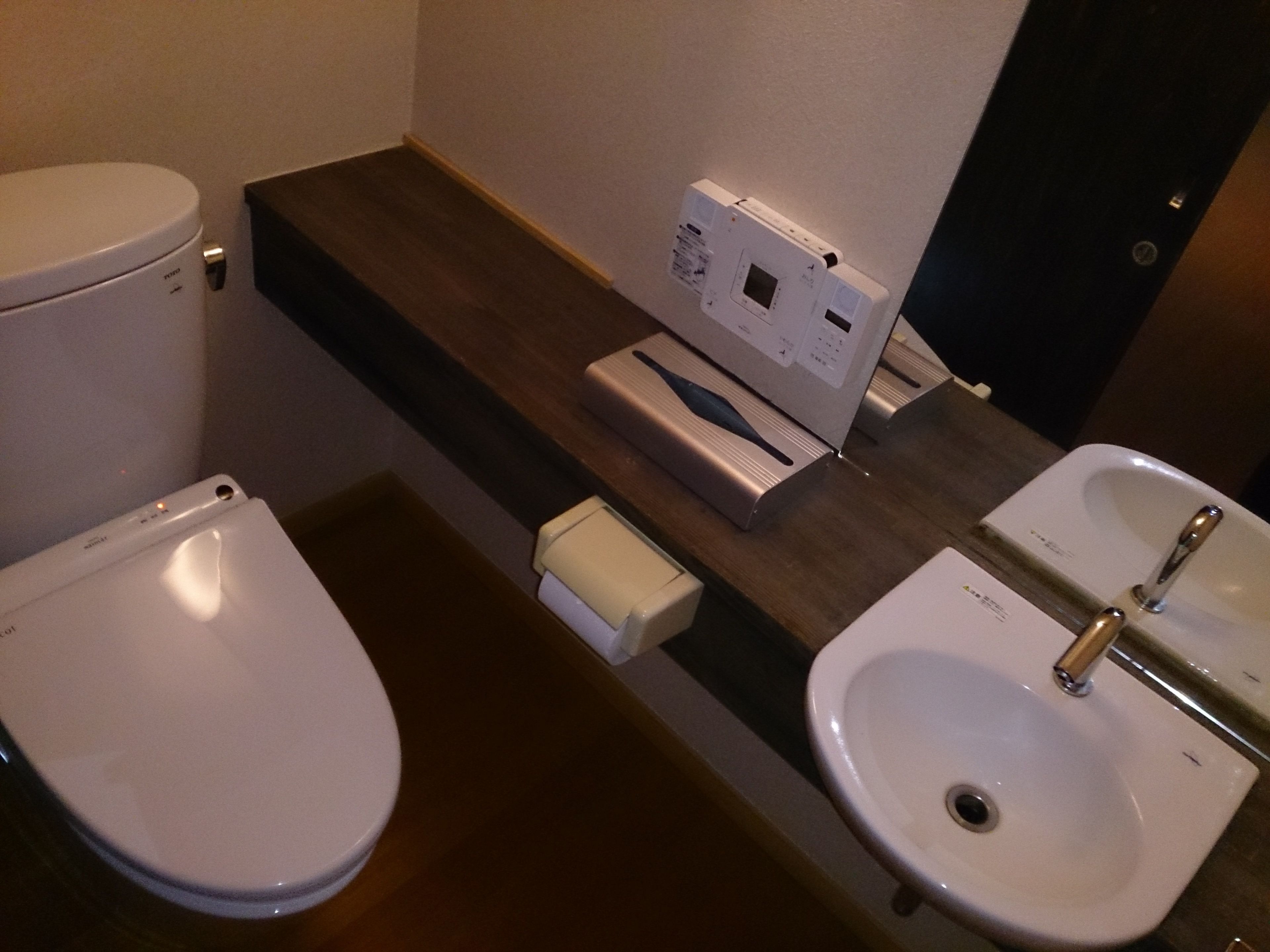 A bathroom with a toilet, a sink, and a paper towel dispenser.