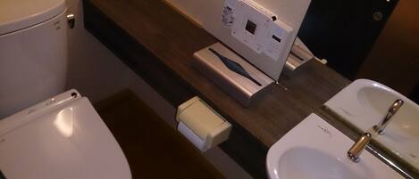 A bathroom with a toilet, a sink, and a paper towel dispenser.