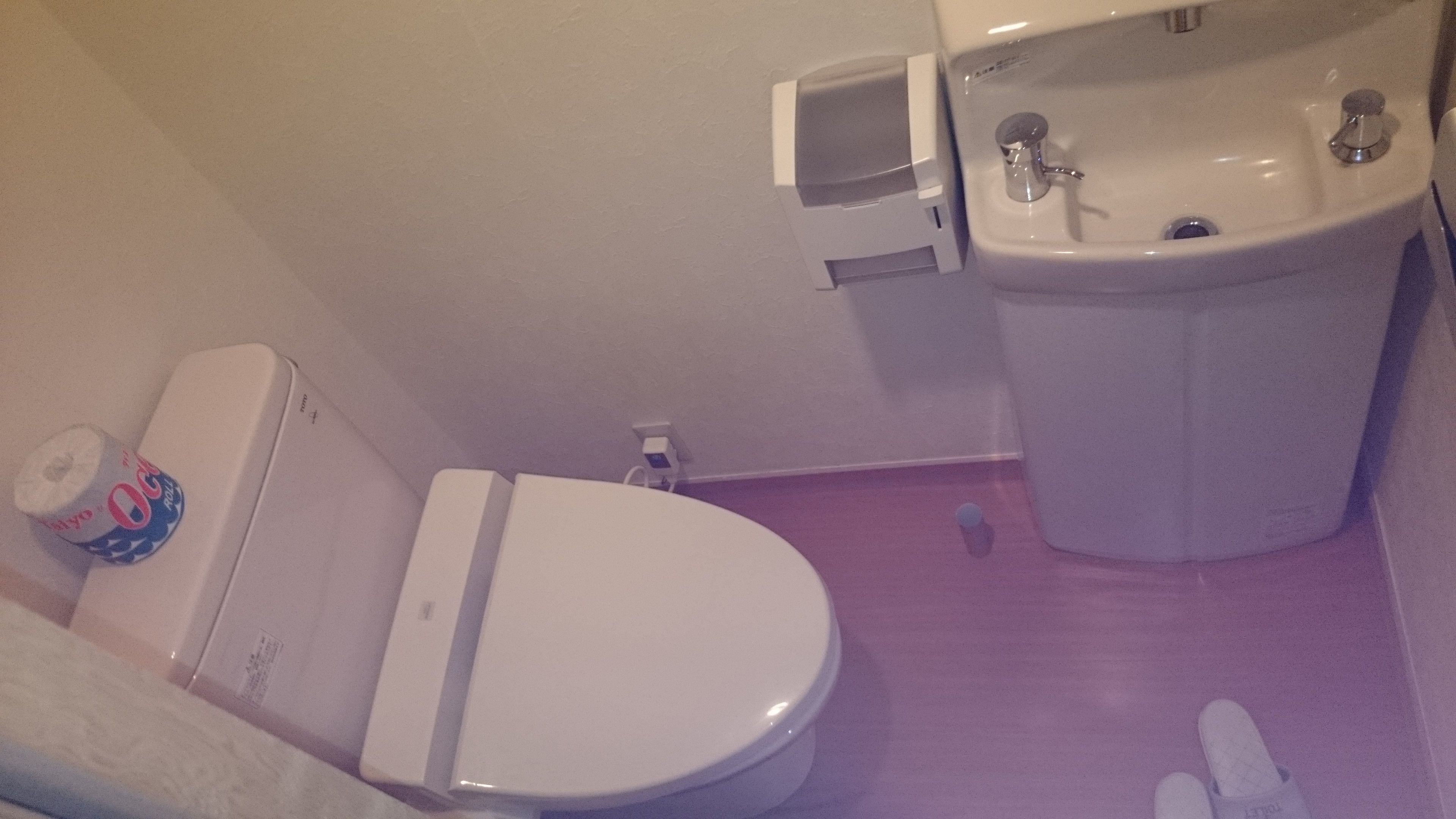 A bathroom with a toilet, sink, and a small trash bin.