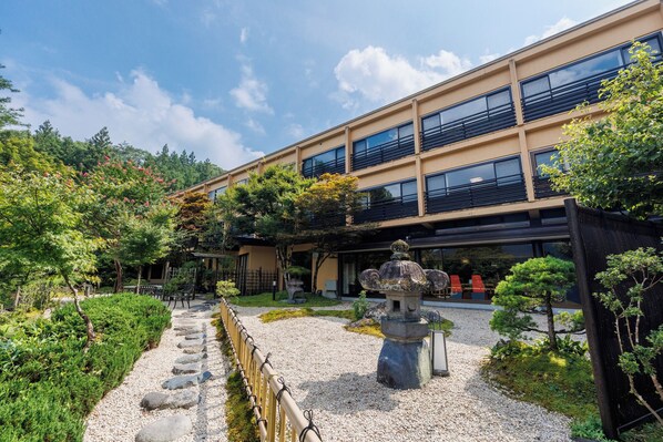 Un edificio con jardín japonés tradicional, que incluye un farol de piedra y un sendero de grava.