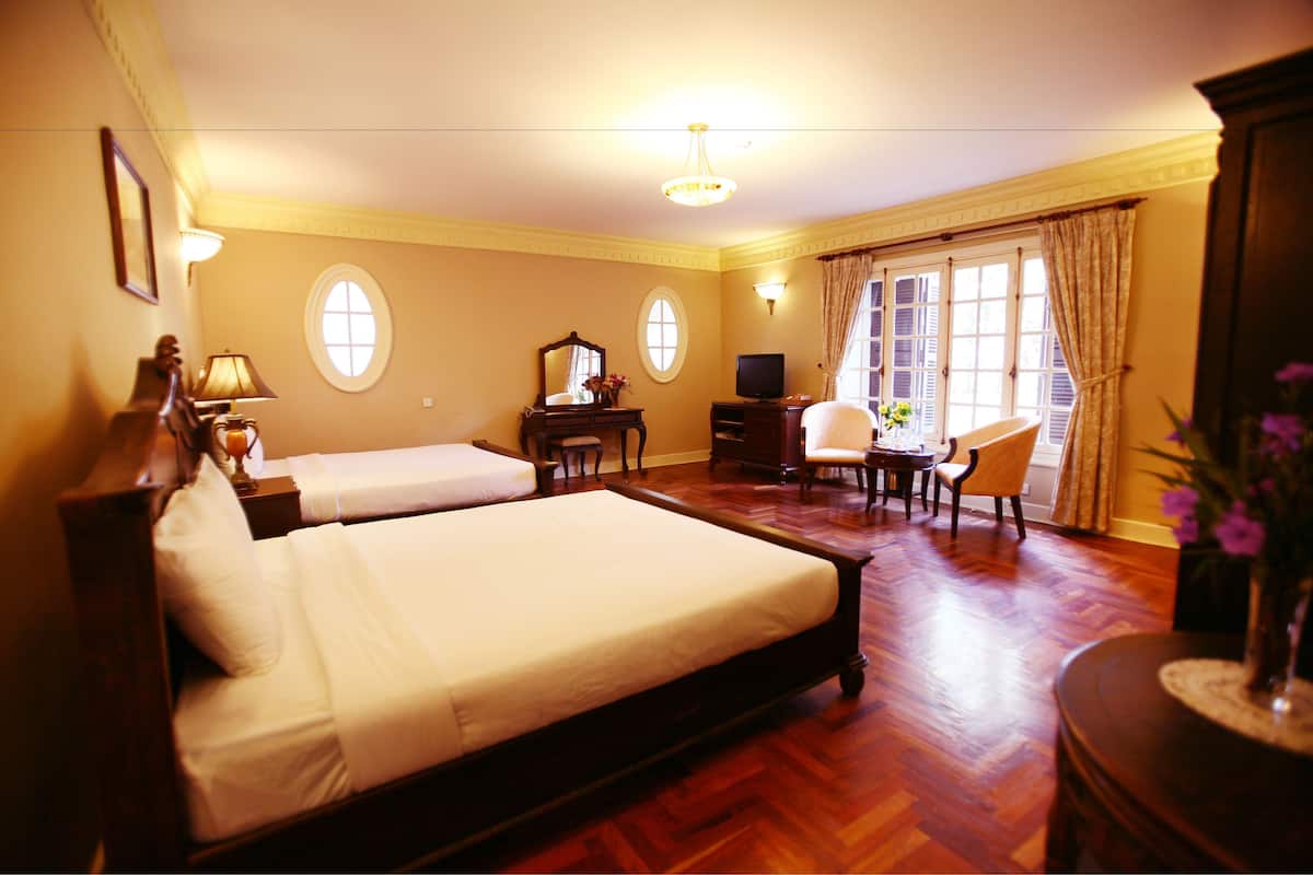Habitación de hotel con dos camas, un escritorio, una silla, un televisor y una ventana con cortinas.