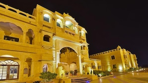 A grand, illuminated building with arched windows and a central entrance, likely a hotel or historic site. - Hotel Desert Tulip (Jaisalmer)