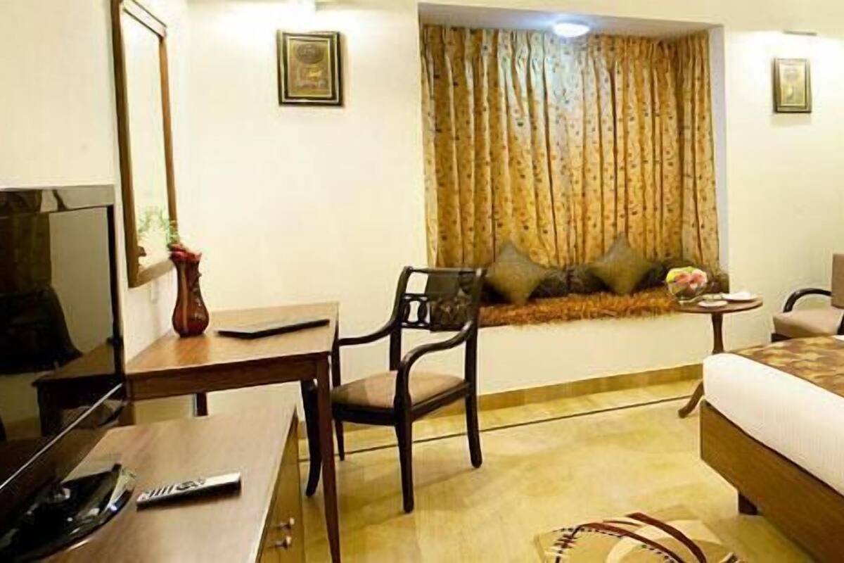 A hotel room with a bed, a desk, a chair, a television, and a window with curtains.