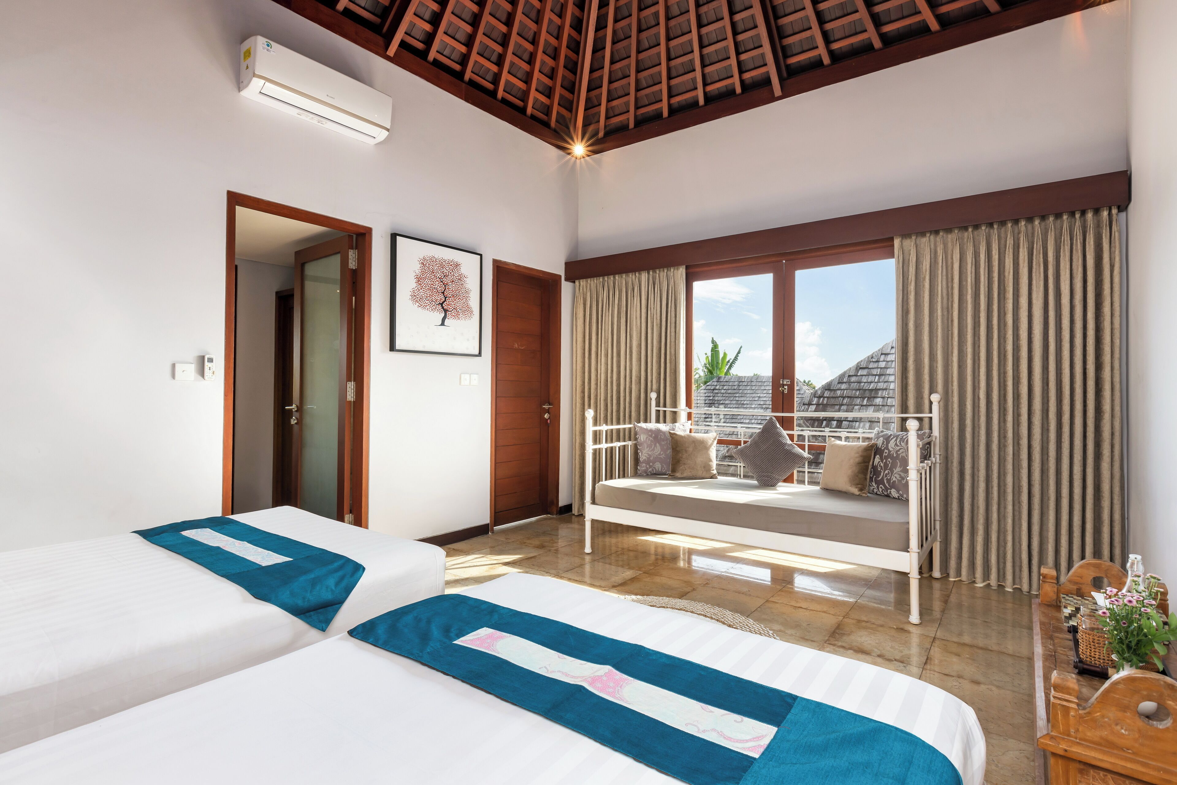 Une chambre d’hôtel avec deux lits, un balcon avec vue et un ventilateur de plafond.