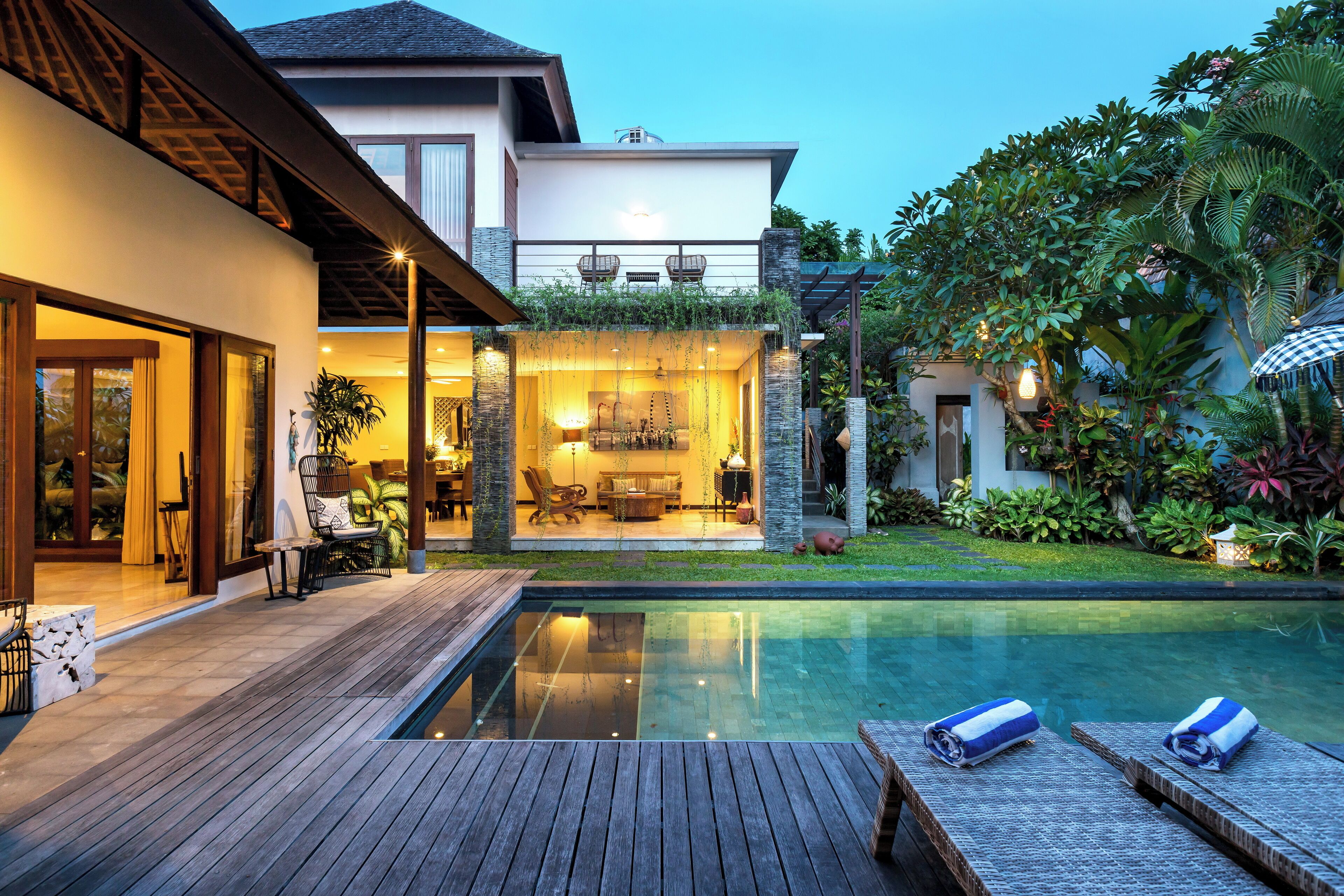 A modern house with a swimming pool, wooden deck, and outdoor seating area.
