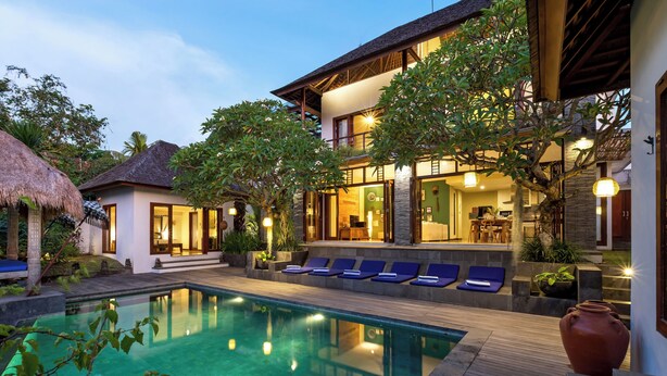 Un resort moderno con piscina, sillas de descanso y un área exterior bien iluminada.