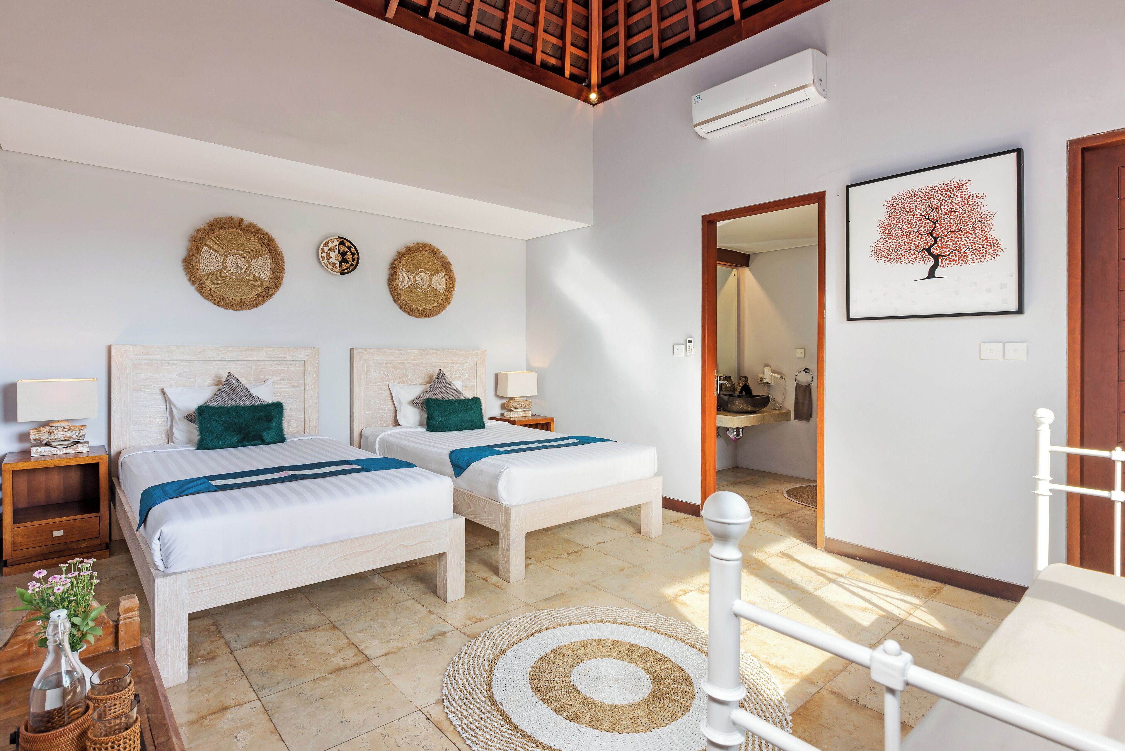 A bedroom with two beds, a wooden ceiling, a woven rug, and a framed picture on the wall.