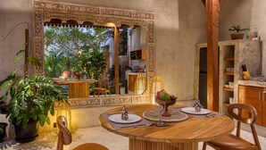Un comedor con una mesa de madera, sillas y un gran espejo decorativo que refleja la habitación.