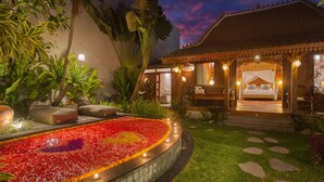 Un edificio de estilo tradicional con una cama, un parterre de flores y una entrada bien iluminada.