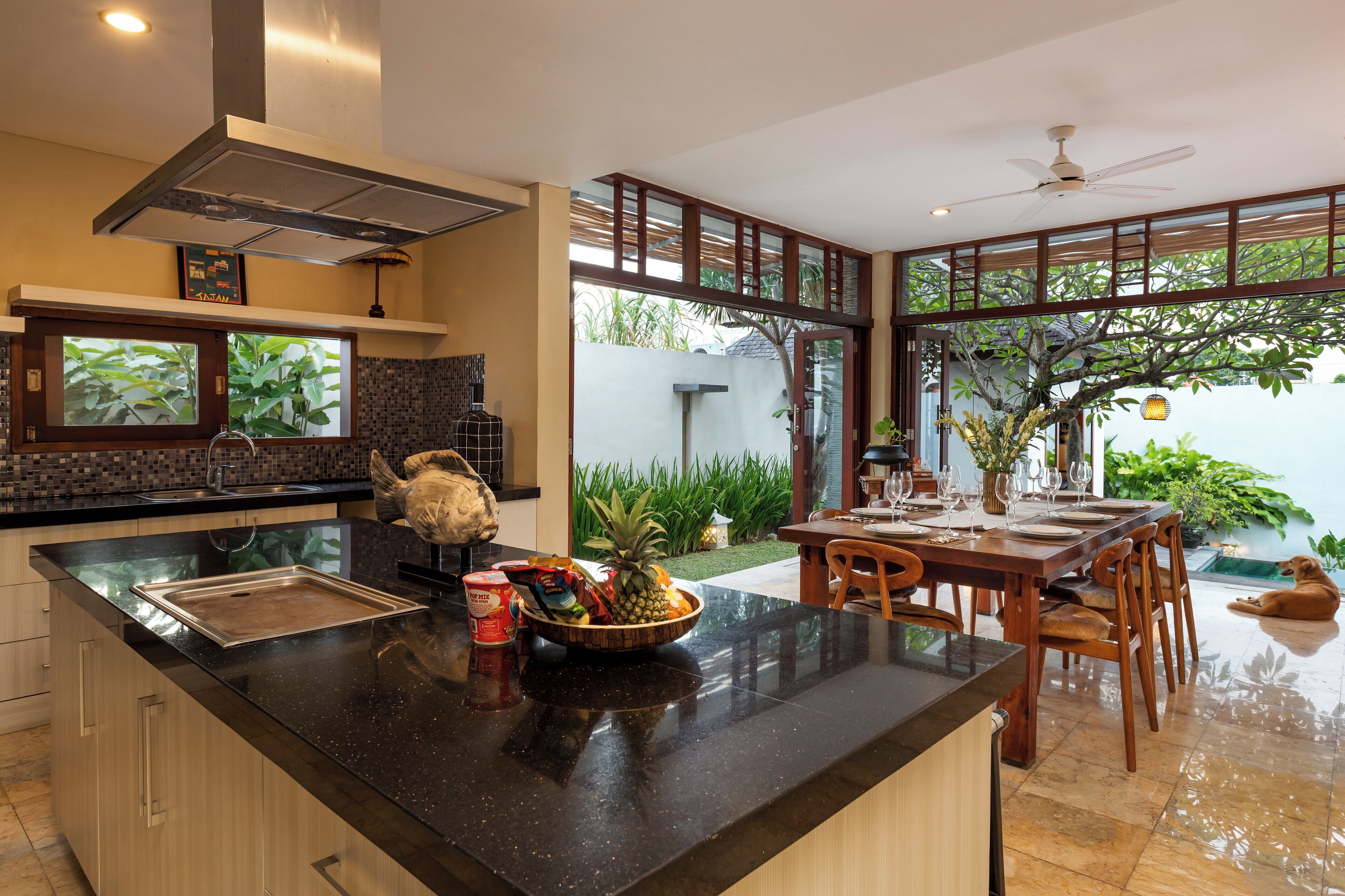 A modern kitchen with a large island, wooden cabinets, and a dining area with a table and chairs.