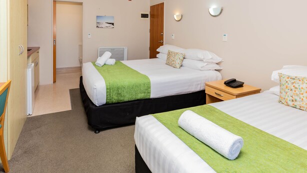 A hotel room with two beds, a desk, a phone, and a bathroom visible through an open door.