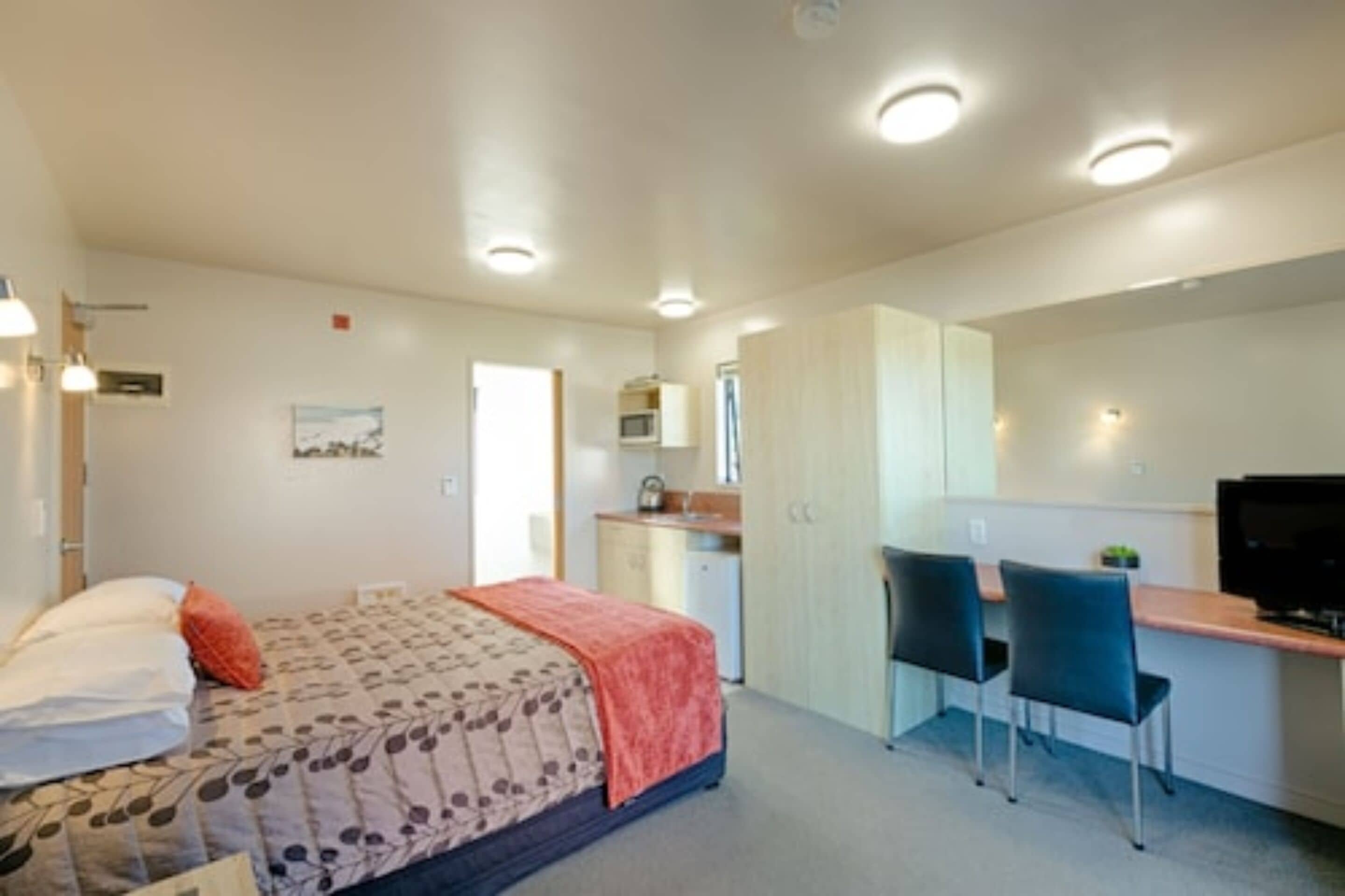A bedroom with a bed, a desk, and a television.