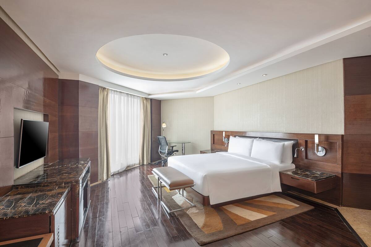 Een moderne hotelkamer met een groot bed, een flatscreen televisie, een bureau en een zithoek.