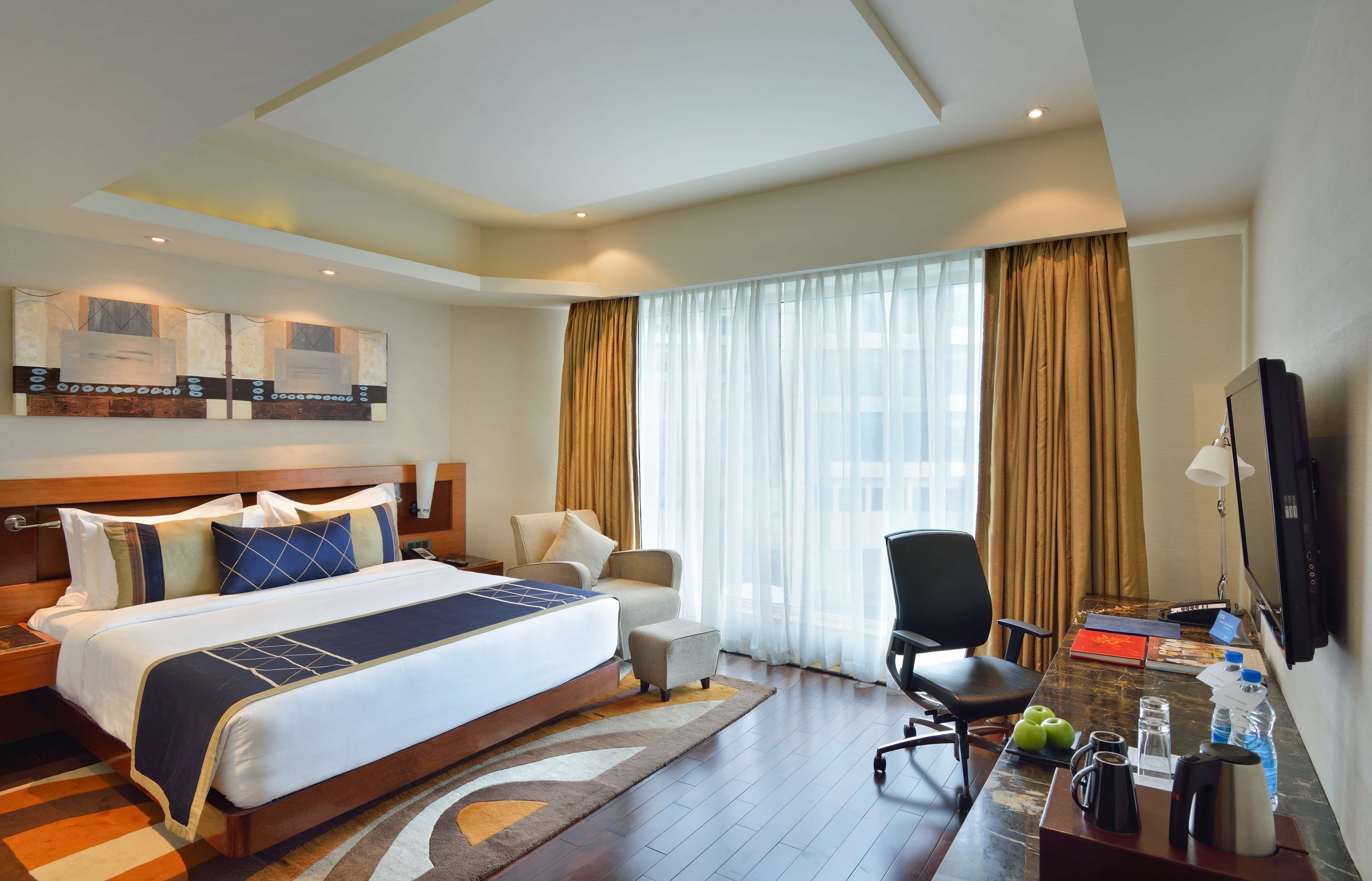 Une chambre d’hôtel avec un grand lit, un bureau avec un ordinateur, une chaise et une télévision.