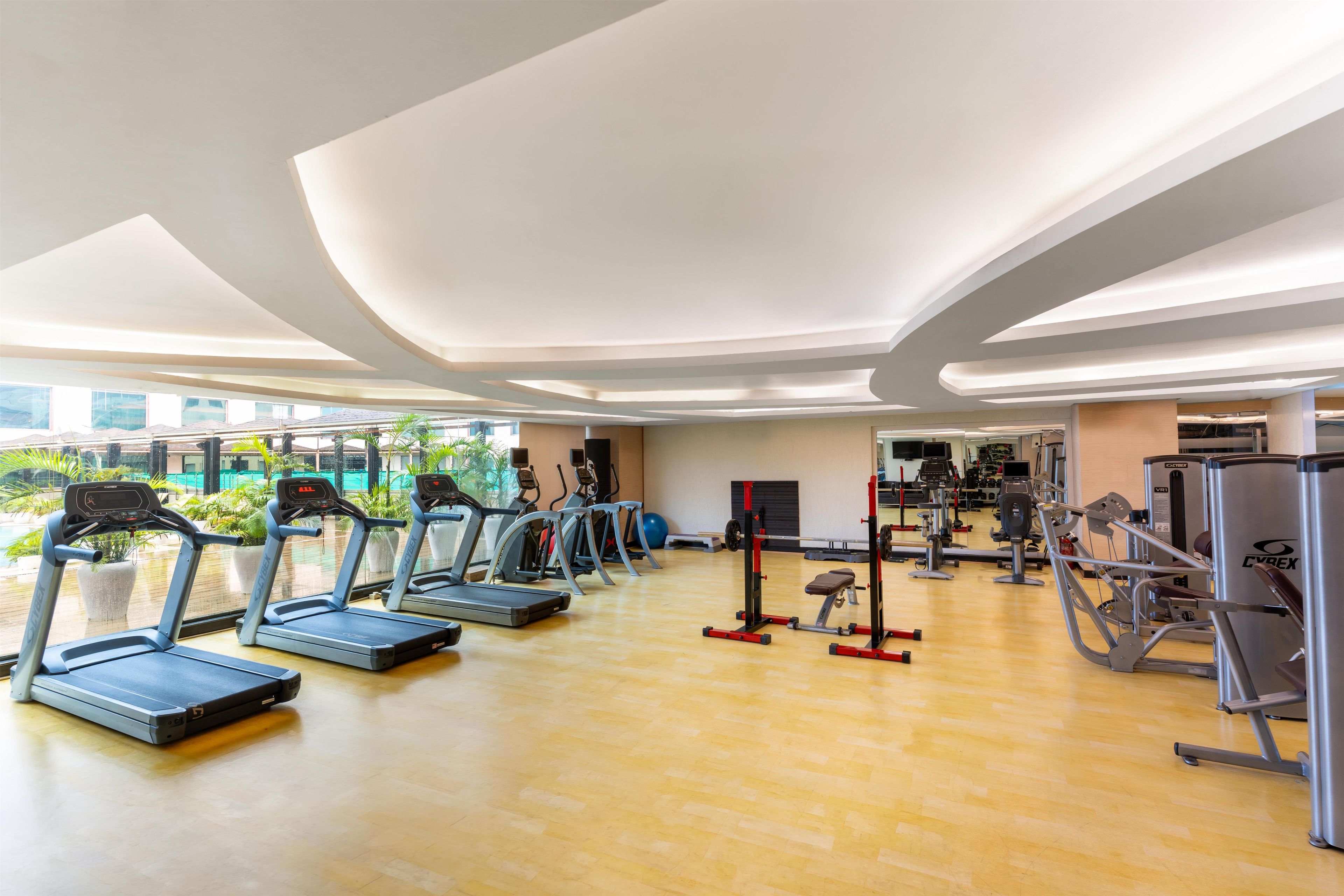 A gym with treadmills, weight machines, and a wooden floor.