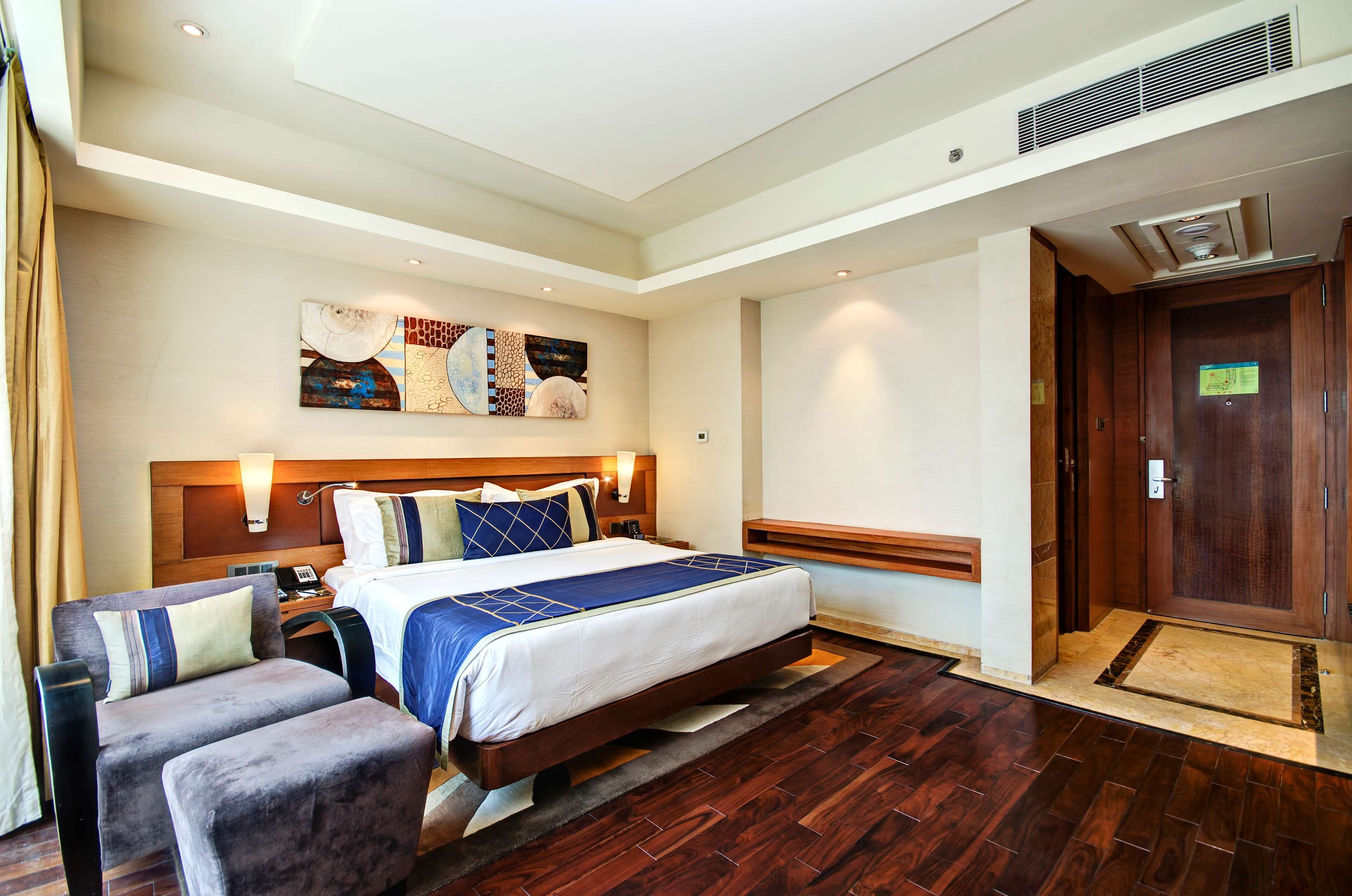 Une chambre d’hôtel avec un grand lit, un bureau, une chaise et une œuvre d’art accrochée au mur.