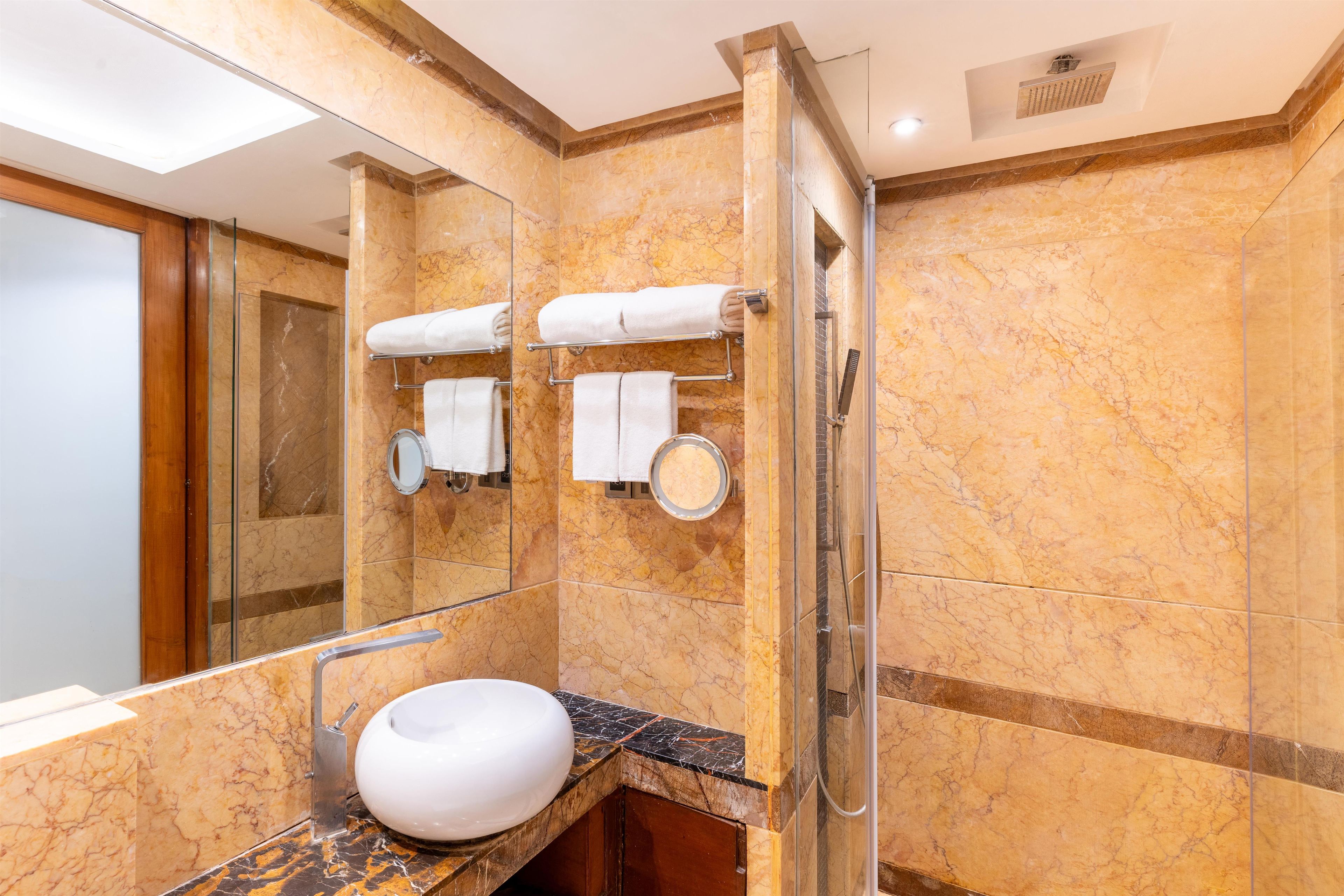 Un baño con lavamanos de mármol, toalleros y una ducha.