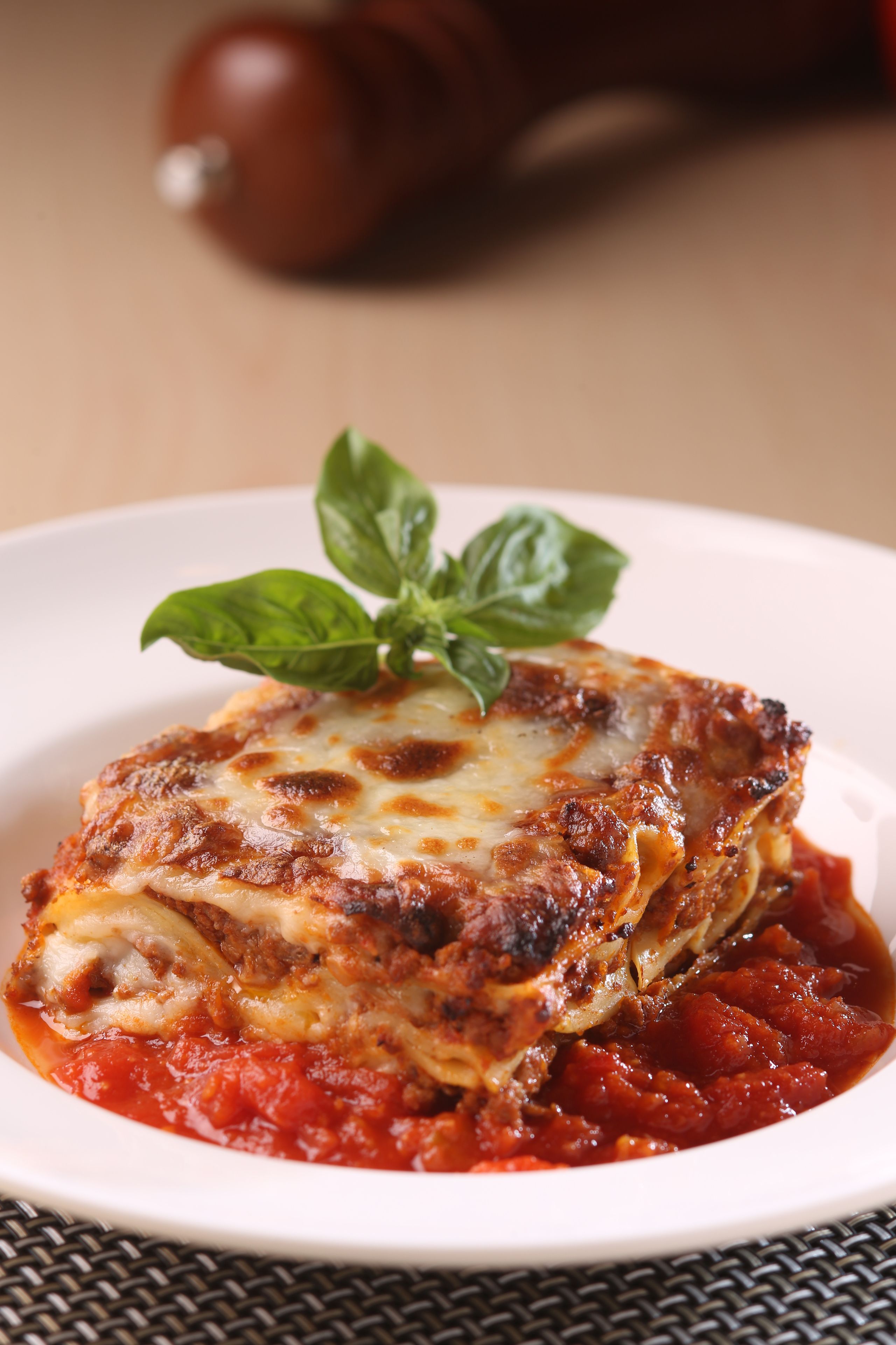 A plate of lasagna with a basil leaf garnish.