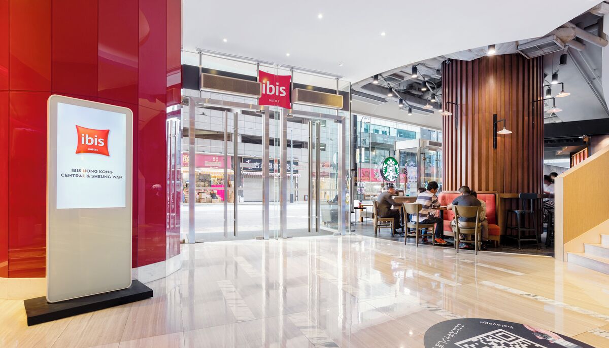A hotel entrance with a glass door, a signboard, and a Starbucks inside.