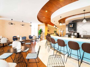 Una zona de bar moderna con una barra curva, taburetes y una máquina de café.