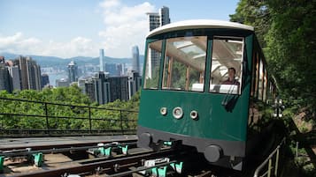 A green cable car with a clear view of a cityscape in the background.