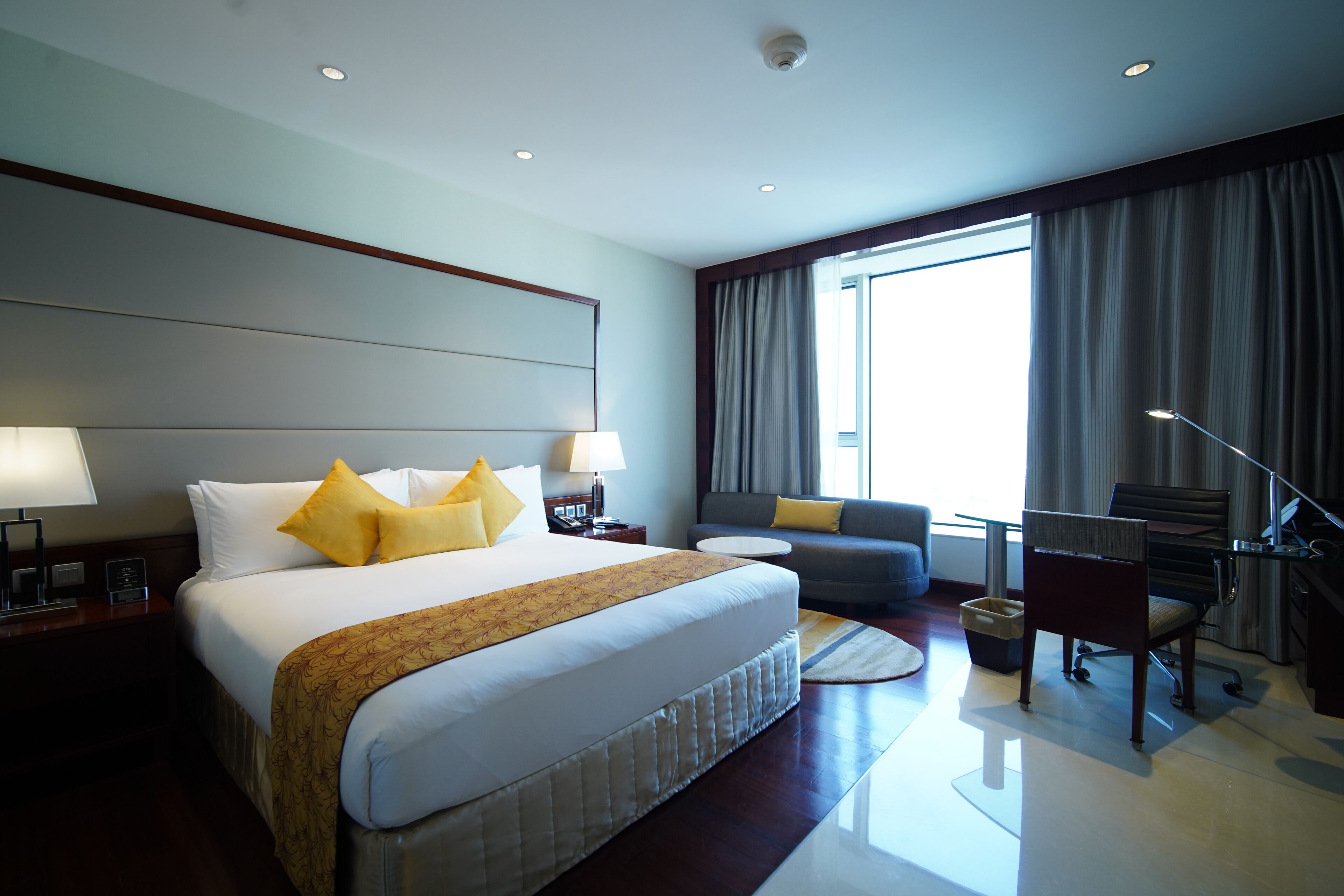A hotel room with a large bed, a sofa, a desk, and a chair.