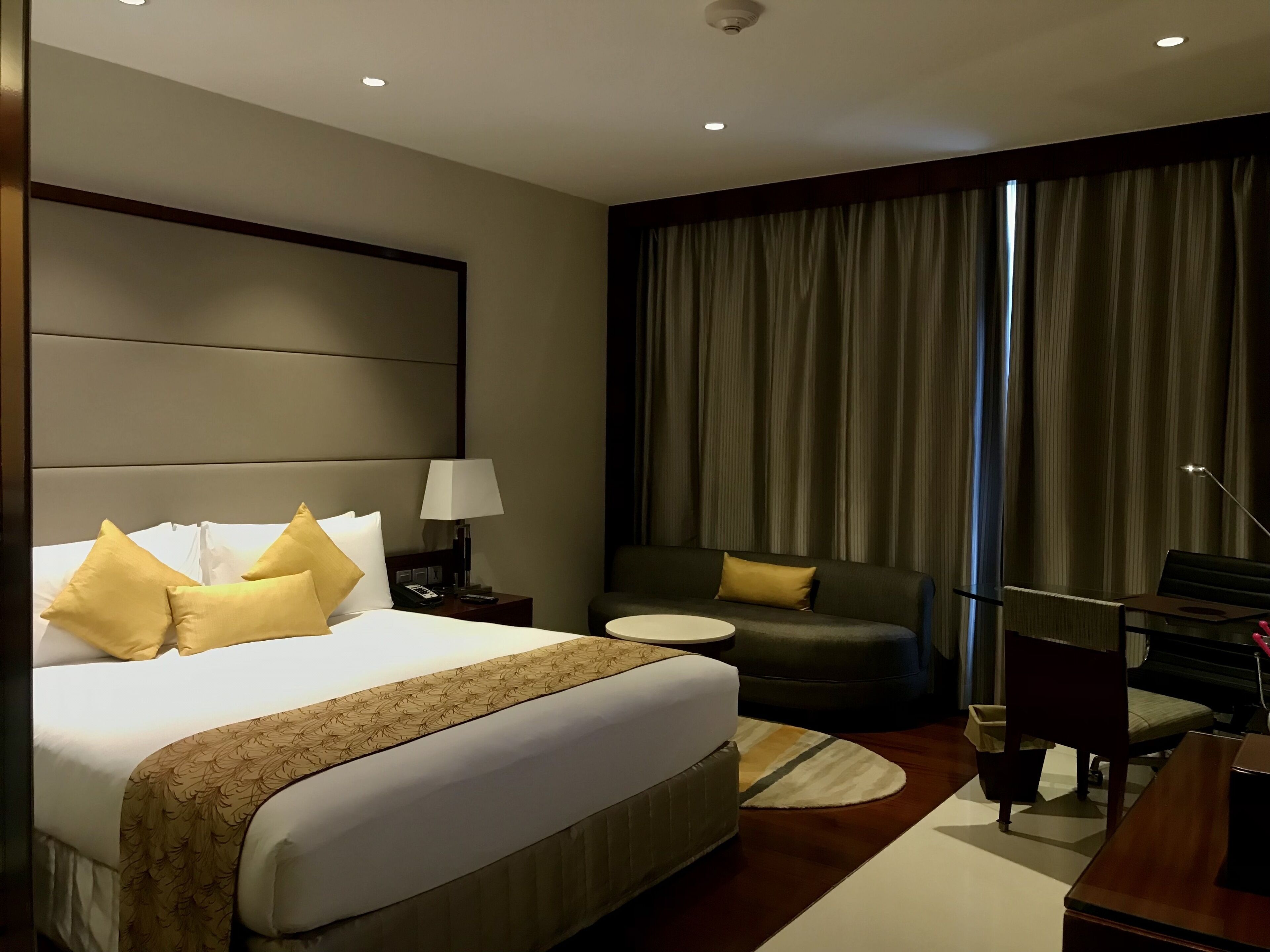 A hotel room with a large bed, a desk, a chair, and a sofa.