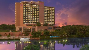A high-rise hotel with multiple floors, a swimming pool, and a dock with a boat. - Crowne Plaza Kochi by IHG (Kanayannur)