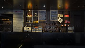 A bar area with shelves of various beverages, a coffee machine, and a chalkboard menu listing drinks.