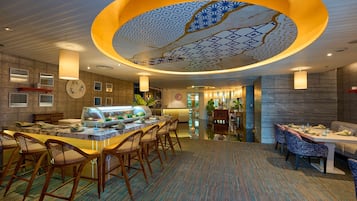 Un vestíbulo de hotel con una zona de bar central, arreglos de asientos y un techo decorativo.