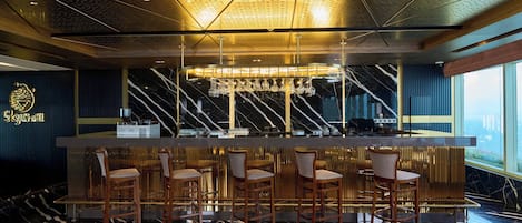 A bar area with a marble floor, bar stools, a bar counter, and a ceiling with a perforated design.
