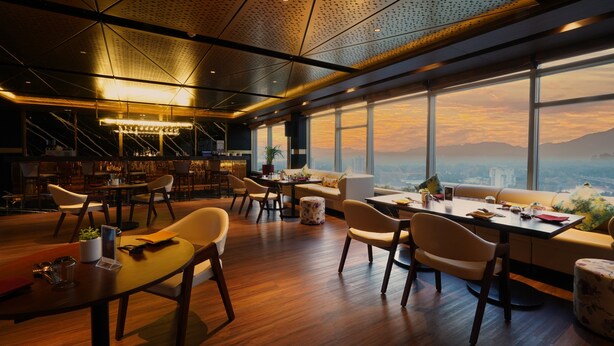 A modern interior with a high ceiling, large windows offering a city view, and a bar area with seating. - Crowne Plaza Kochi by IHG (Kanayannur)