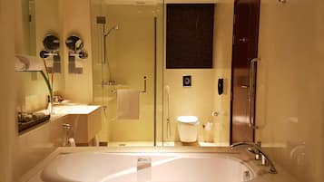 A modern bathroom with a large bathtub, a glass-enclosed shower, and a toilet.