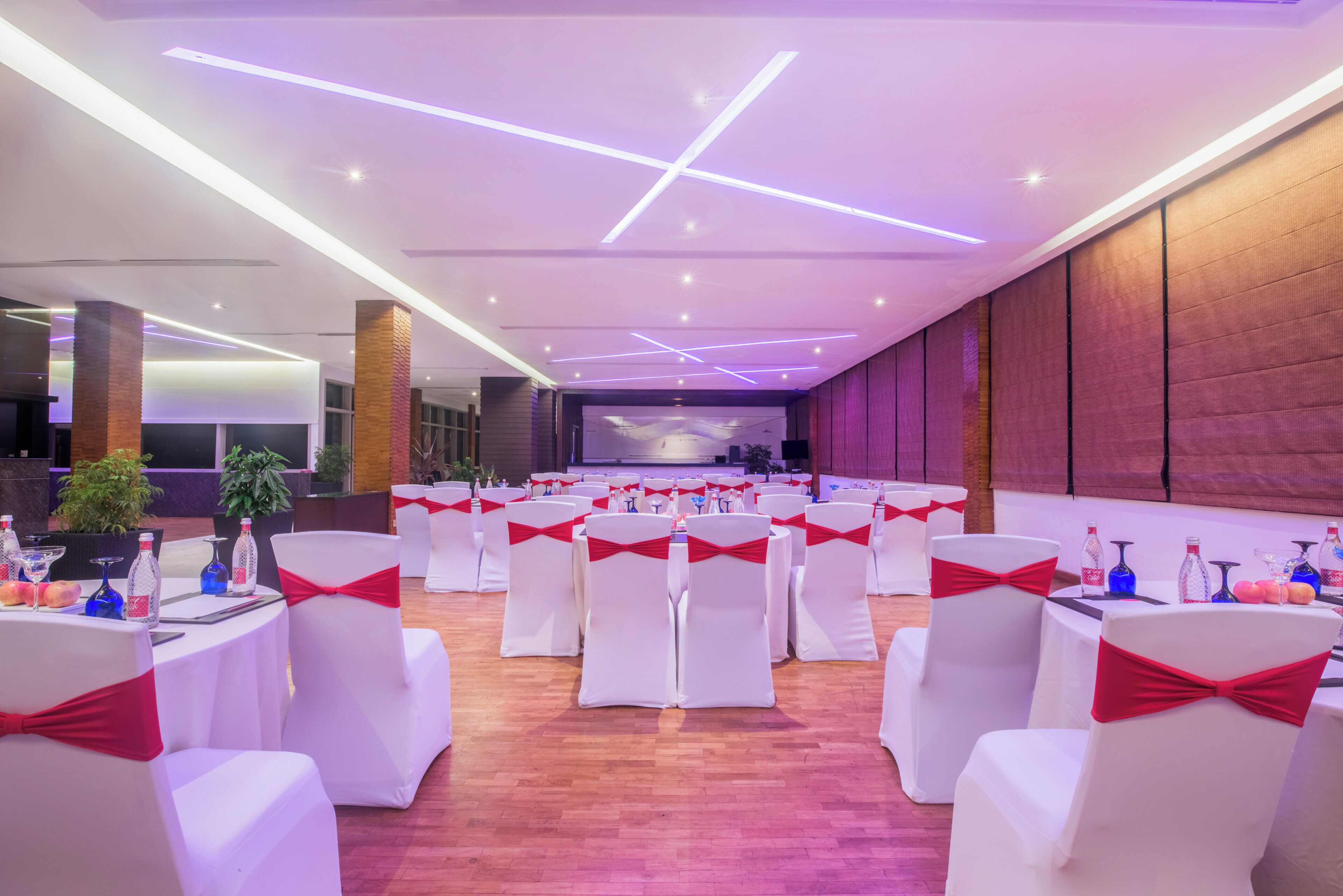 A conference room with white chairs, red bows, and tables set for a meeting.