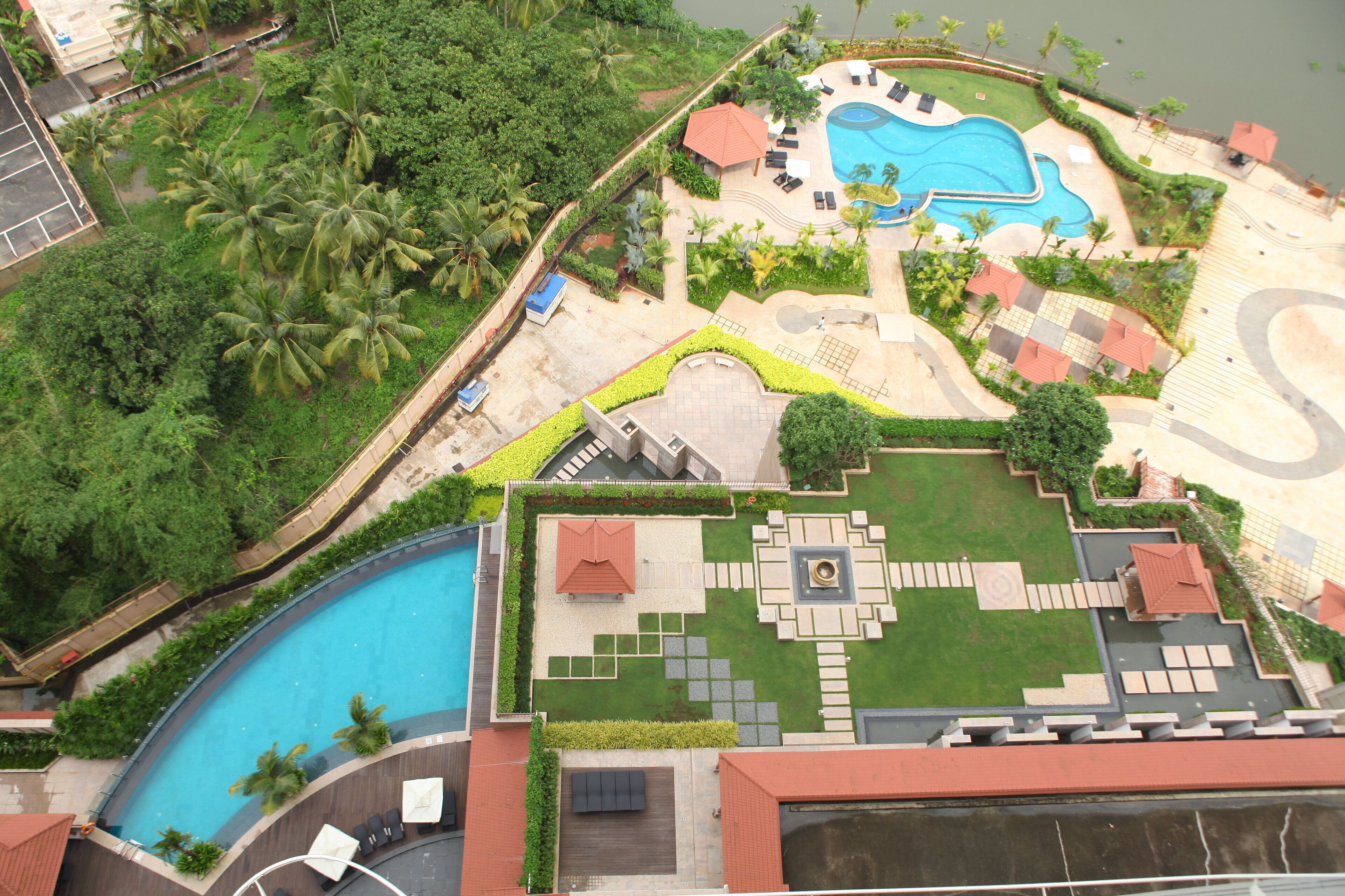 An aerial view of a resort with a swimming pool, lounge areas, and landscaped gardens.