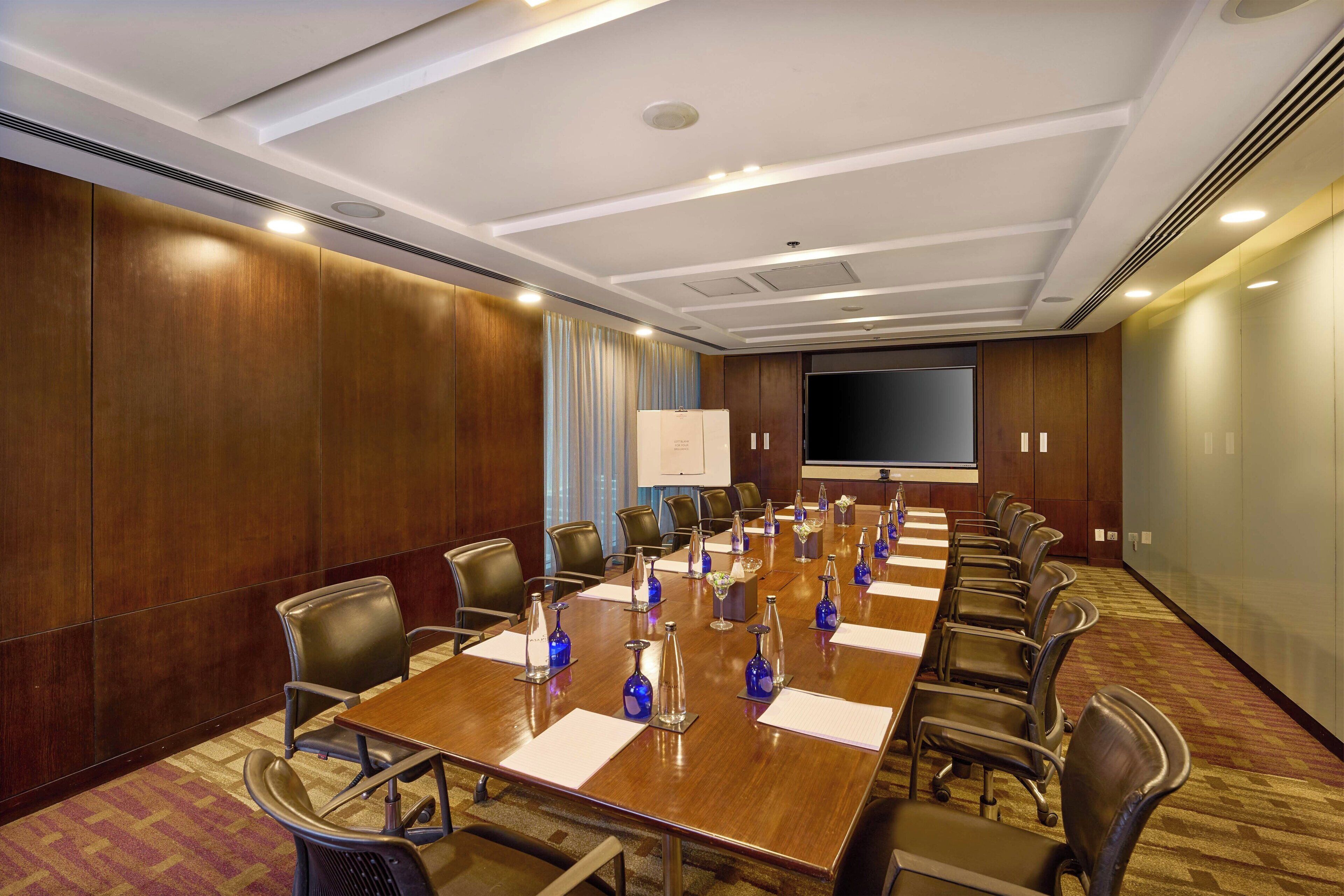 A conference room with a long table, chairs, and a projector screen.