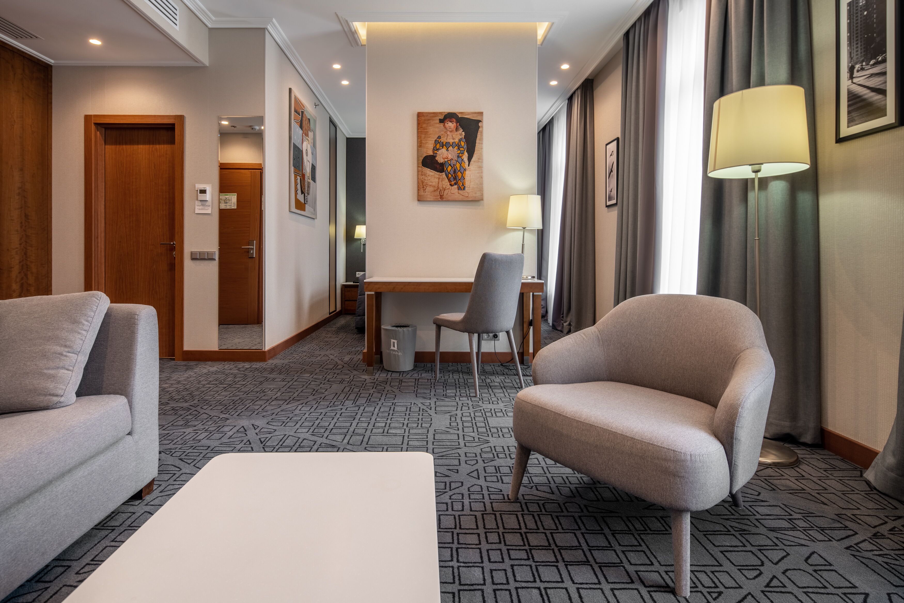 Une chambre d’hôtel avec un canapé, un fauteuil, une table à manger et un tableau au mur.