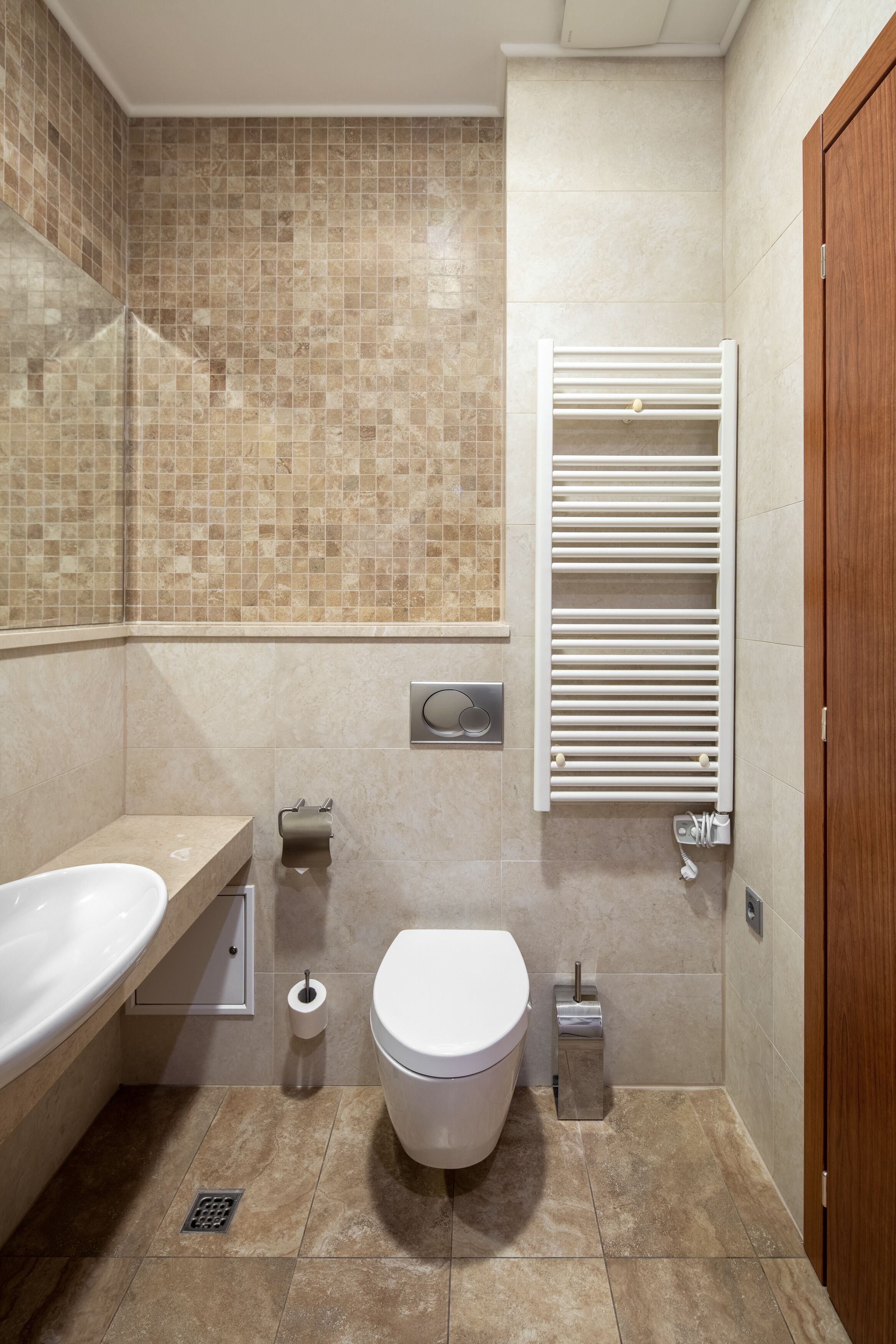 A modern bathroom with a bathtub, toilet, and towel rack.