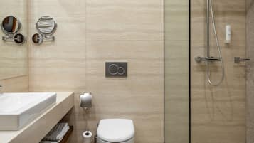 Een moderne badkamer met een glazen douchecabine, een wit toilet en een wastafel met spiegel en handdoekhouder.
