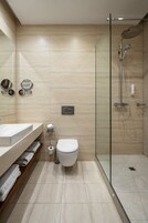 Een moderne badkamer met een glazen douchecabine, een wit toilet en een wastafel met spiegel en handdoekhouder.