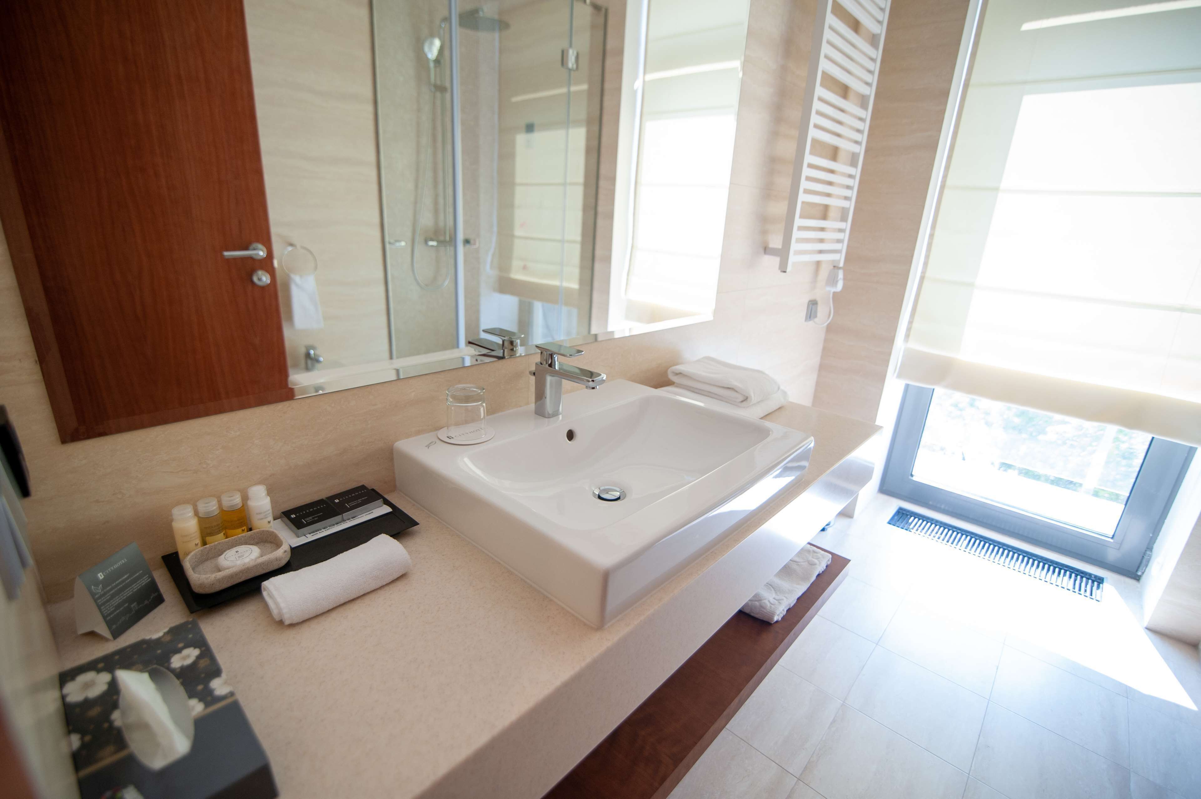 A modern bathroom with a large sink, a mirror, and a window.