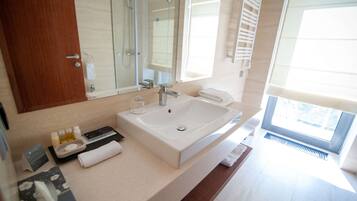 A modern bathroom with a large sink, a mirror, and a window.