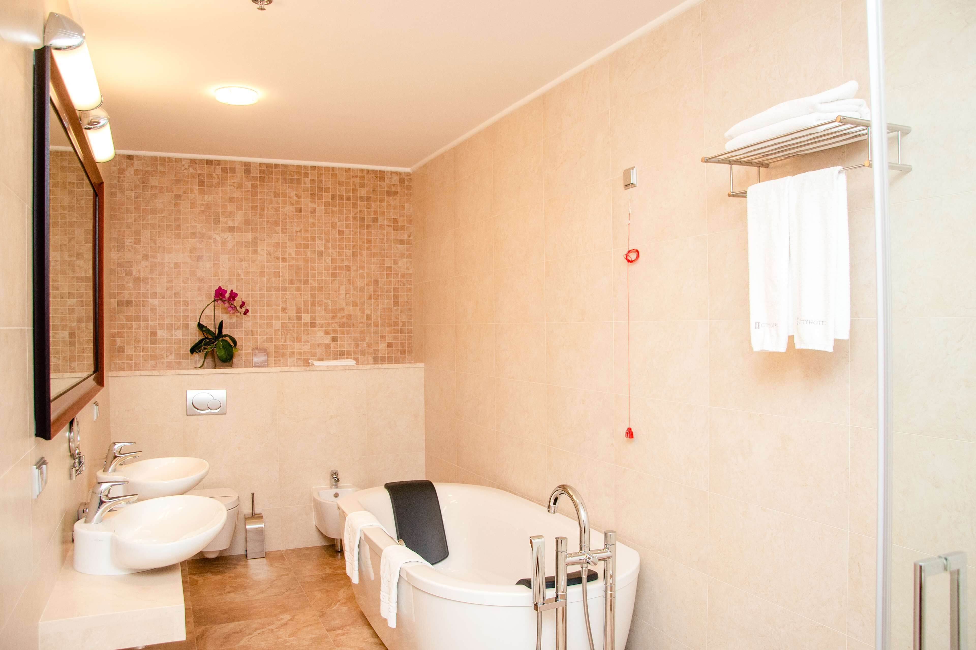 Ein modernes Badezimmer mit einer freistehenden Badewanne, zwei Waschbecken, einer Toilette und einem Spiegel.